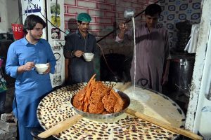 A vendor displays traditional sweet milk jalebi and dates, attracting people to enjoy the seasonal winter treat at Chowk Noonarian