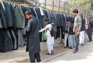 People browse and buy overcoats displayed on footpaths to keep themselves warm as the arrival of winter and temperatures dropping in the city.