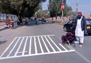 Labourer paint a zebra crossing on the road.