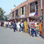 Cricket lovers stand in queue at the entry gate of Iqbal Stadium to attend the first ODI match between Pakistan and South Africa