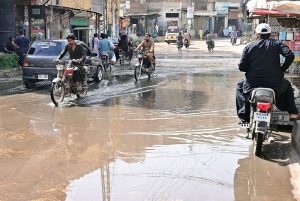 Motorcyclists pass through accumulated sewage water on Pakka Fort Road. The stagnant water poses health risks, including the potential spread of dengue, prompting calls for prompt action by local authorities.