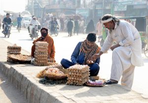 Vendors arrange and sell desi hen eggs to passersby at a roadside stall along Vehari Road as demand rises with the drop in temperature.