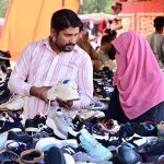 A couple purchases second-hand shoes from a roadside vendor at Makki Shah Road.