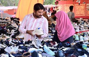 A couple purchases second-hand shoes from a roadside vendor at Makki Shah Road.