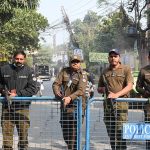 Police personnel stand alert during the by-election in National Assembly constituency NA-129 at Sodiwal