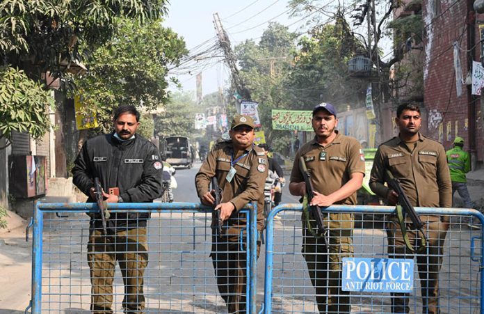 Police personnel stand alert during the by-election in National Assembly constituency NA-129 at Sodiwal