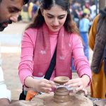 A visitor engages in the traditional art of clay pot making at a stall during the ten-day annual folk festival “Lok Mela 2025” at Lok Virsa, Islamabad