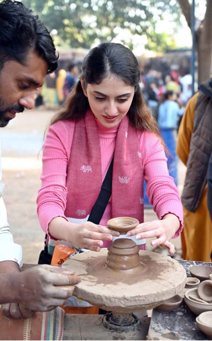A visitor engages in the traditional art of clay pot making at a stall during the ten-day annual folk festival “Lok Mela 2025” at Lok Virsa, Islamabad