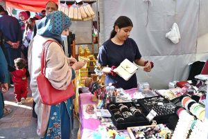 A visitor engages in the traditional art of clay pot making at a stall during the ten-day annual folk festival “Lok Mela 2025” at Lok Virsa, Islamabad
