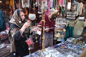 A visitor engages in the traditional art of clay pot making at a stall during the ten-day annual folk festival “Lok Mela 2025” at Lok Virsa, Islamabad