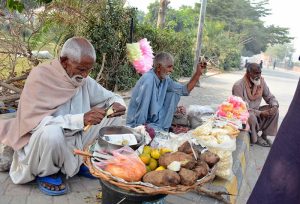 Elderly vendors selling sweet potatoes and cotton candy at roadside in Qasim Bagh, striving to earn their livelihood through honest labor.