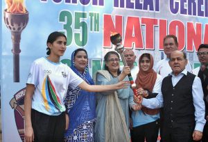 Khwaja Idrees, representing the Punjab Olympic Association, hands over the torch to athletes Vice Chancellor Dr. Uzma Qureshi and Dr. Sameera Sattarat during the 35th National Games torch relay ceremony at Lahore College for Women.