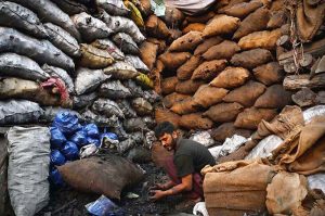 A worker packs charcoal in bags for customers after receiving it from a coal mine at his workplace in the provincial capital.