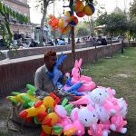 A balloon seller offers a variety of children’s toy balloons on the Green Belt to earn a living for his family in the city.