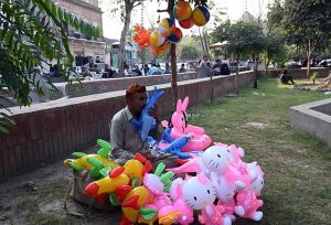A balloon seller offers a variety of children’s toy balloons on the Green Belt to earn a living for his family in the city.