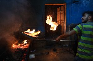 A cook prepares fish over a coal fire in the Keamari Food Street.
