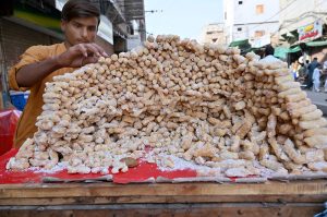 A vendor selling traditional sweet items at Jinnah Bagh Road