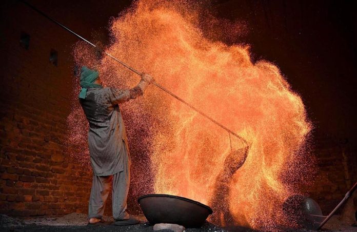 A worker prepares a traditional coal oven to steam corn at his workplace before it is sold to vendors in the provincial capital
