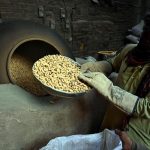 A worker roasts peanuts in a traditional oven for customers at his workplace in the provincial capital.