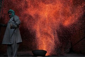A worker prepares a traditional coal oven to steam corn at his workplace before it is sold to vendors in the provincial capital