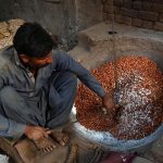 A worker roasts almonds at his workplace for supply to various markets, as the demand for dry fruits rises with the dropping temperatures in the provincial capital.