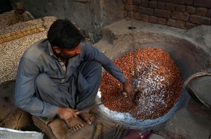 A worker roasts almonds at his workplace for supply to various markets, as the demand for dry fruits rises with the dropping temperatures in the provincial capital.