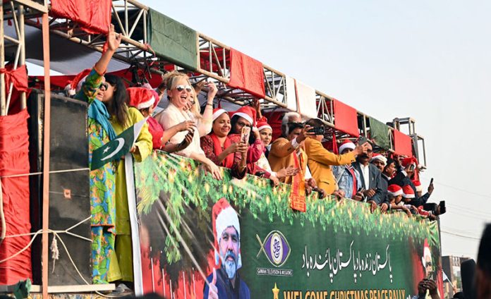 Foreigners wave to participants during the Welcome Christmas Rally