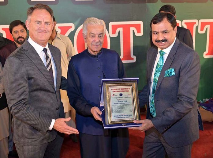 Senior Pastor Anwar Afzal presenting a shield to Defense Minister Khawaja Muhammad Asif at prayer ceremony for the Christian community at City Ground