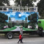 Woman with children walk past a mobile automatic air quality monitoring station parking along a roadside to mentor air quality index in the Provincial Capital