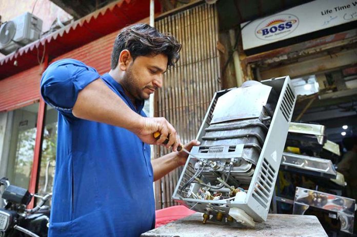 Mechanic busy in repairing instant geyser at his workplace near Khyber Bazar