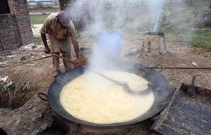 A farmer preparing gur (jaggery) in a traditional way from sugarcane juice at his farm
