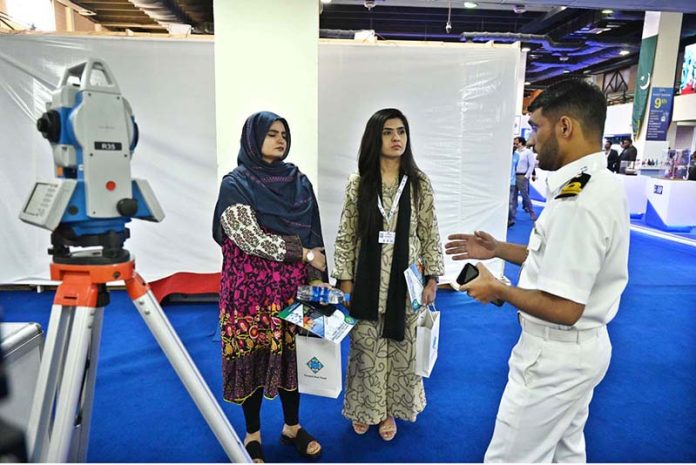 A naval officer briefing female visitors at a stall established during the 2nd Edition of Pakistan International Maritime Expo and Conference 2025 at Expo Centre