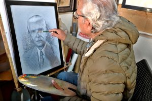 An artist puts the final touches on a portrait of Quaid-e-Azam Muhammad Ali Jinnah ahead of his birth anniversary .