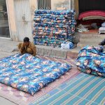 Workers stitch and fill traditional cotton quilts at a roadside setup to meet the rising winter demand