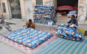 Workers stitch and fill traditional cotton quilts at a roadside setup to meet the rising winter demand