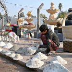A young worker arranging decoration stuff and plants pots to attract the customers at local nursery, Chak Shehzad Road.