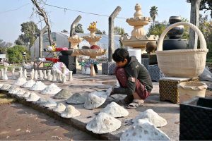 A young worker arranging decoration stuff and plants pots to attract the customers at local nursery, Chak Shehzad Road.