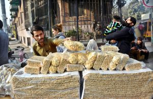 A vendor displays Pop Corns and Muranda, a traditional sweet snack in South Asia, a crunchy laddu made from puffed rice or wheat mixed with jaggery, often associated with a baby's naming ceremony, at his roadside stall to attract customers.
