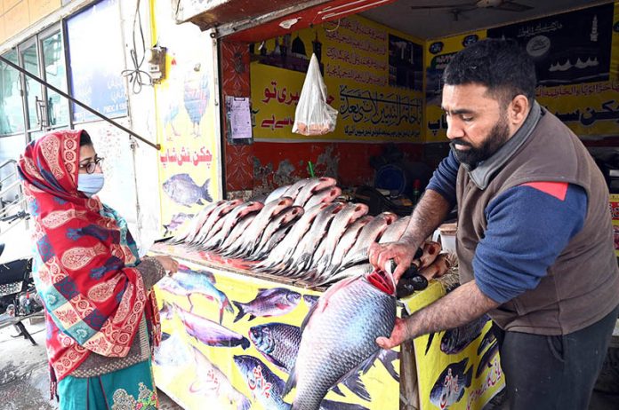 vendor sells fresh fish to a woman at Millat Road