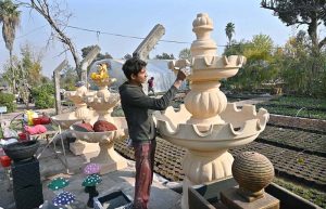 A young worker arranging decoration stuff and plants pots to attract the customers at local nursery, Chak Shehzad Road.