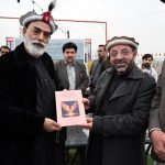 Qazi Inayat Jalil Anbar, a prominent Khowar literature writer, poet, and radio host, presents his book to Senator Talha Mahmood during the ceremony marking the launch of his new book “Sada Bahar Khowar Geet” (Volume I)