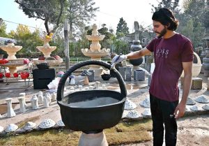 A young worker arranging decoration stuff and plants pots to attract the customers at local nursery, Chak Shehzad Road.