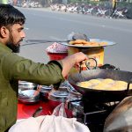 A vendor prepares fresh laddoos for sale at a roadside stall in the city.