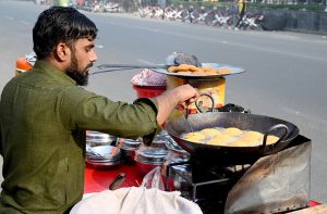 A vendor prepares fresh laddoos for sale at a roadside stall in the city.