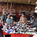 A vendor displays shoes to attract customers under the Makki Shah Flyover.