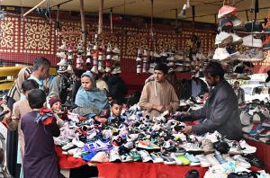 A vendor displays shoes to attract customers under the Makki Shah Flyover.