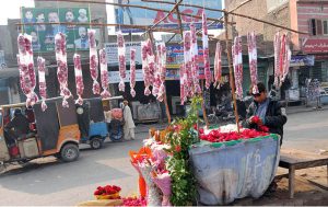 A young street vendor preparing fresh rose garlands at a roadside flower stall.