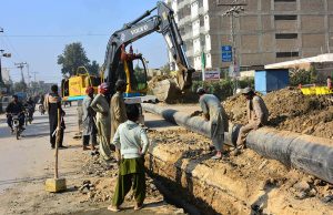 Labourers carry out sewerage pipeline construction using heavy machinery in Latifabad as part of ongoing development work.