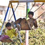 Children enjoying swing on a vendor’s roadside setup at Latifabad.