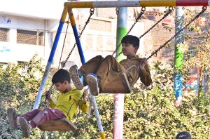 Children enjoying swing on a vendor’s roadside setup at Latifabad.